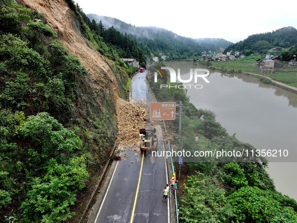 Workers are driving machinery and equipment to clear landslide soil at the site of a landslide in Datong Township on G242 National Highway i...