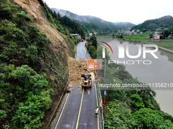 Workers are driving machinery and equipment to clear landslide soil at the site of a landslide in Datong Township on G242 National Highway i...