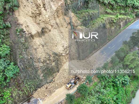 Workers are driving machinery and equipment to clear landslide soil at the site of a landslide in Datong Township on G242 National Highway i...