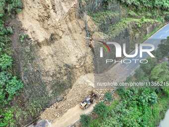 Workers are driving machinery and equipment to clear landslide soil at the site of a landslide in Datong Township on G242 National Highway i...