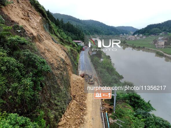 Workers are driving machinery and equipment to clear landslide soil at the site of a landslide in Datong Township on G242 National Highway i...