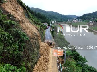 Workers are driving machinery and equipment to clear landslide soil at the site of a landslide in Datong Township on G242 National Highway i...