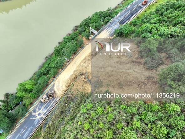 Workers are driving machinery and equipment to clear landslide soil at the site of a landslide in Datong Township on G242 National Highway i...