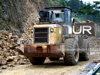 Workers are driving machinery and equipment to clear landslide soil at the site of a landslide in Datong Township on G242 National Highway i...