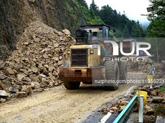 Workers are driving machinery and equipment to clear landslide soil at the site of a landslide in Datong Township on G242 National Highway i...