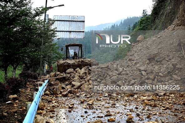 Workers are driving machinery and equipment to clear landslide soil at the site of a landslide in Datong Township on G242 National Highway i...