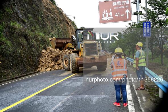 Workers are driving machinery and equipment to clear landslide soil at the site of a landslide in Datong Township on G242 National Highway i...