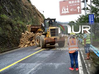 Workers are driving machinery and equipment to clear landslide soil at the site of a landslide in Datong Township on G242 National Highway i...