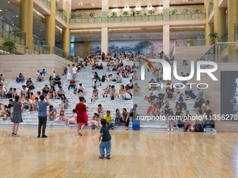 People are sitting on the steps of the hall of Shandong Museum to cool off in Jinan, China, on June 23, 2024. (