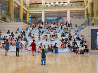 People are sitting on the steps of the hall of Shandong Museum to cool off in Jinan, China, on June 23, 2024. (