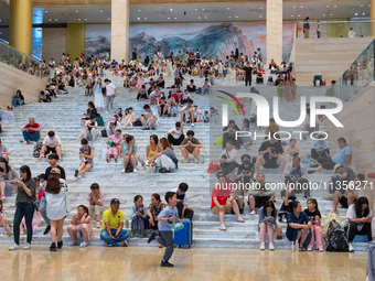 People are sitting on the steps of the hall of Shandong Museum to cool off in Jinan, China, on June 23, 2024. (