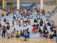 People are sitting on the steps of the hall of Shandong Museum to cool off in Jinan, China, on June 23, 2024. (