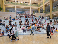 People are sitting on the steps of the hall of Shandong Museum to cool off in Jinan, China, on June 23, 2024. (