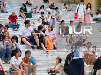 People are sitting on the steps of the hall of Shandong Museum to cool off in Jinan, China, on June 23, 2024. (