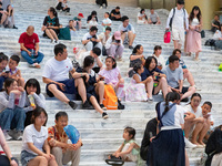 People are sitting on the steps of the hall of Shandong Museum to cool off in Jinan, China, on June 23, 2024. (