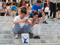 People are sitting on the steps of the hall of Shandong Museum to cool off in Jinan, China, on June 23, 2024. (