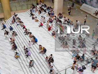 People are sitting on the steps of the hall of Shandong Museum to cool off in Jinan, China, on June 23, 2024. (