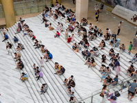 People are sitting on the steps of the hall of Shandong Museum to cool off in Jinan, China, on June 23, 2024. (