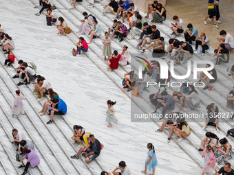 People are sitting on the steps of the hall of Shandong Museum to cool off in Jinan, China, on June 23, 2024. (