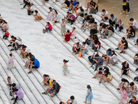 People are sitting on the steps of the hall of Shandong Museum to cool off in Jinan, China, on June 23, 2024. (