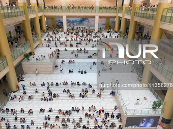 People are sitting on the steps of the hall of Shandong Museum to cool off in Jinan, China, on June 23, 2024. (