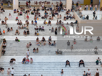 People are sitting on the steps of the hall of Shandong Museum to cool off in Jinan, China, on June 23, 2024. (