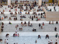 People are sitting on the steps of the hall of Shandong Museum to cool off in Jinan, China, on June 23, 2024. (