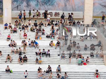 People are sitting on the steps of the hall of Shandong Museum to cool off in Jinan, China, on June 23, 2024. (