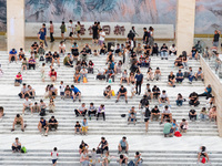 People are sitting on the steps of the hall of Shandong Museum to cool off in Jinan, China, on June 23, 2024. (