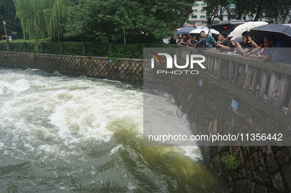 Tourists are watching the Shengtang Gate discharge water from the lake of West Lake in Hangzhou, China, on June 24, 2024. On the same day, t...