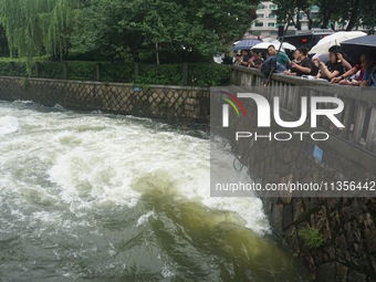 Tourists are watching the Shengtang Gate discharge water from the lake of West Lake in Hangzhou, China, on June 24, 2024. On the same day, t...