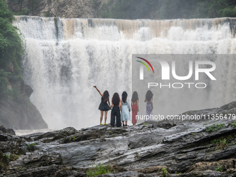 Tourists are enjoying cooling off at the Diaolan Waterfall in Xiangshui township of Bijie city, in Bijie, China, on June 23, 2024. (