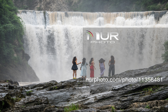 Tourists are enjoying cooling off at the Diaolan Waterfall in Xiangshui township of Bijie city, in Bijie, China, on June 23, 2024. 