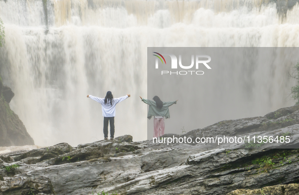 Tourists are enjoying cooling off at the Diaolan Waterfall in Xiangshui township of Bijie city, in Bijie, China, on June 23, 2024. 