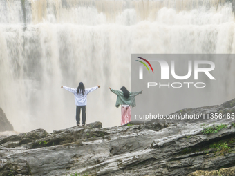 Tourists are enjoying cooling off at the Diaolan Waterfall in Xiangshui township of Bijie city, in Bijie, China, on June 23, 2024. (