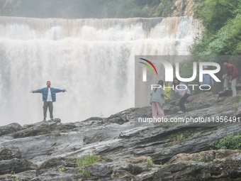 Tourists are enjoying cooling off at the Diaolan Waterfall in Xiangshui township of Bijie city, in Bijie, China, on June 23, 2024. (