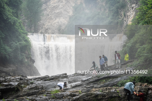 Tourists are enjoying cooling off at the Diaolan Waterfall in Xiangshui township of Bijie city, in Bijie, China, on June 23, 2024. 