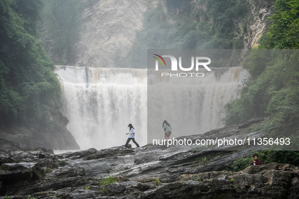 Tourists are enjoying cooling off at the Diaolan Waterfall in Xiangshui township of Bijie city, in Bijie, China, on June 23, 2024. 