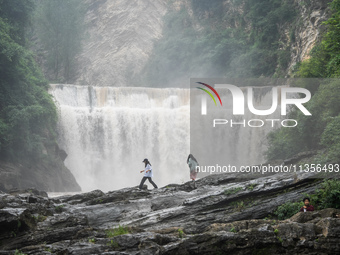 Tourists are enjoying cooling off at the Diaolan Waterfall in Xiangshui township of Bijie city, in Bijie, China, on June 23, 2024. (