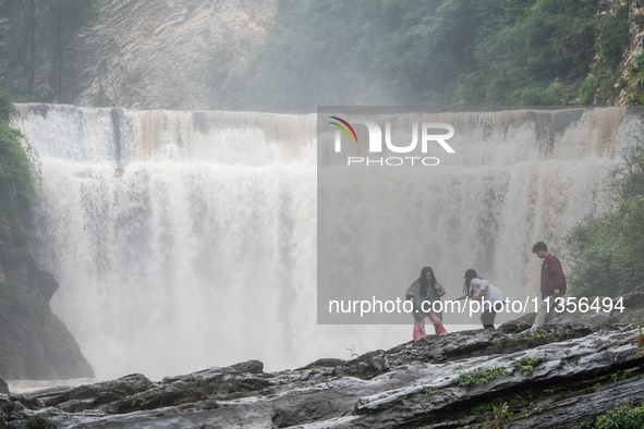 Tourists are enjoying cooling off at the Diaolan Waterfall in Xiangshui township of Bijie city, in Bijie, China, on June 23, 2024. 