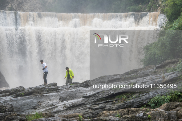 Tourists are enjoying cooling off at the Diaolan Waterfall in Xiangshui township of Bijie city, in Bijie, China, on June 23, 2024. 