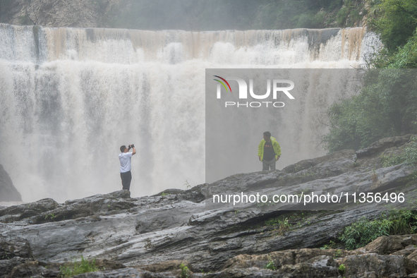 Tourists are enjoying cooling off at the Diaolan Waterfall in Xiangshui township of Bijie city, in Bijie, China, on June 23, 2024. 