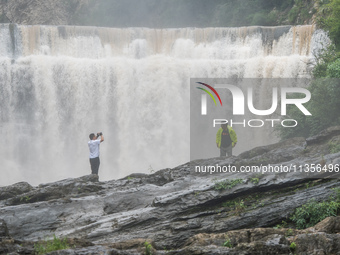 Tourists are enjoying cooling off at the Diaolan Waterfall in Xiangshui township of Bijie city, in Bijie, China, on June 23, 2024. (