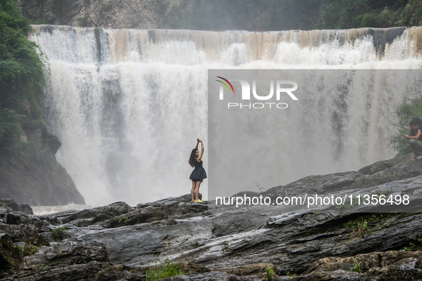 Tourists are enjoying cooling off at the Diaolan Waterfall in Xiangshui township of Bijie city, in Bijie, China, on June 23, 2024. 