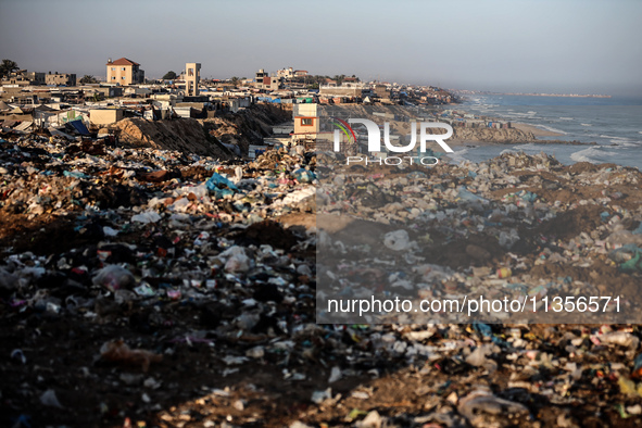 A view is showing piles of garbage next to the tents housing internally displaced Palestinians crowding the beach and the Mediterranean shor...