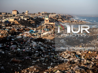 A view is showing piles of garbage next to the tents housing internally displaced Palestinians crowding the beach and the Mediterranean shor...