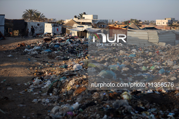 A view is showing piles of garbage next to the tents housing internally displaced Palestinians crowding the beach and the Mediterranean shor...