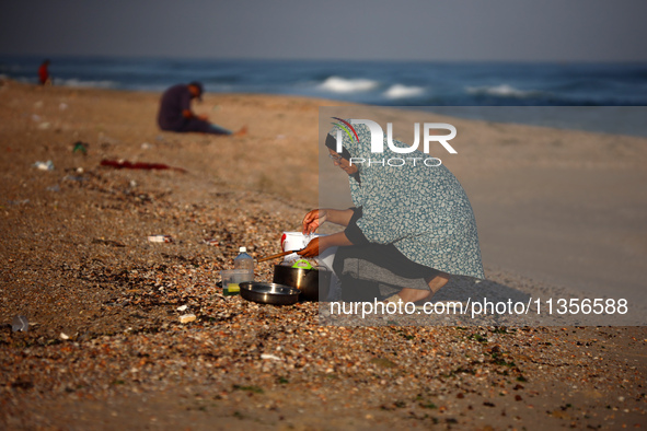 A Palestinian woman is washing kitchenware on the beach in Deir el-Balah, central Gaza Strip, on June 24, 2024, amid the ongoing conflict be...