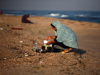 A Palestinian woman is washing kitchenware on the beach in Deir el-Balah, central Gaza Strip, on June 24, 2024, amid the ongoing conflict be...