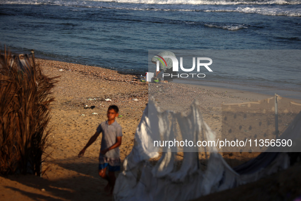 A Palestinian woman is washing kitchenware on the beach in Deir el-Balah, central Gaza Strip, on June 24, 2024, amid the ongoing conflict be...